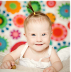 Smiling infant in front of flowered wallpaper