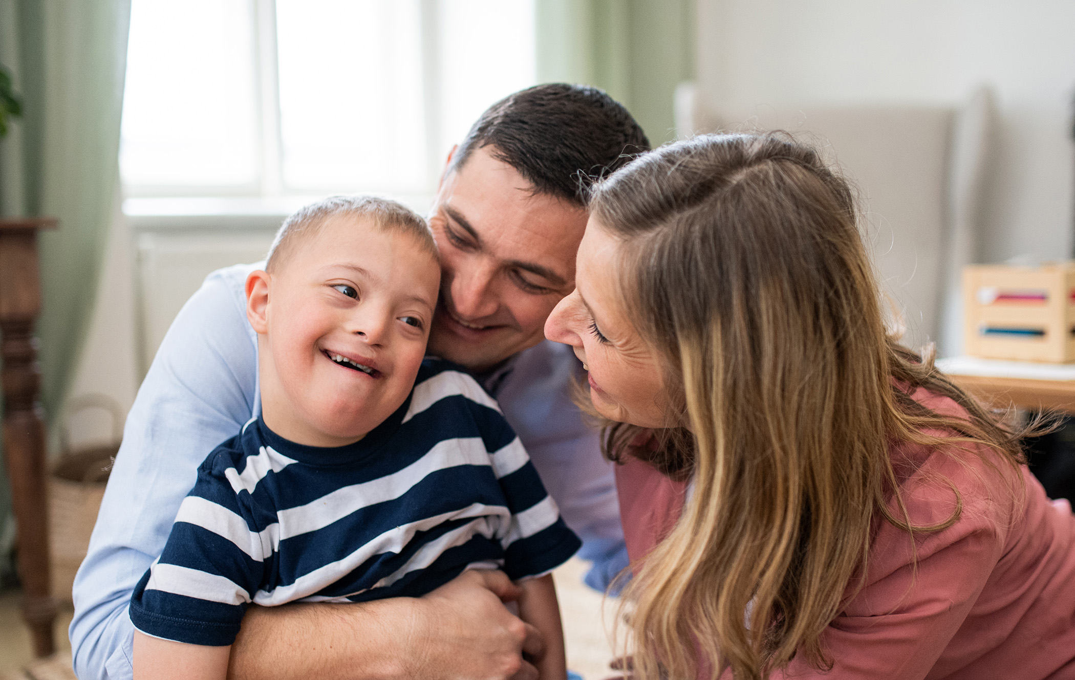 A young boy is hugged by his parents